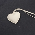 Dettaglio del ciondolo a cuore in pelle bianco crema con cuciture sottili e lacci in pelle - Stile Cordino / Grigio