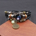 Dettaglio di un bracciale zodiacale Bilancia vintage con cinturini in pelle intrecciata - Bilancia Luminosa