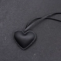 Primo piano di un ciondolo a cuore in pelle nera con cuciture dettagliate e cordino nero - Stile Cordino / Nero