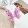 Close-up of a double-layered butterfly hair claw clip with pink crystals on a white tray - Metallic Purple