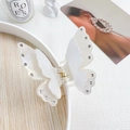 Macro detail of the metal spring mechanism on a white butterfly rhinestone hair claw - Mermaid White