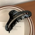 Détail d'une pince à cheveux noire avec logo France doré posée sur une assiette - 11cm / Noir
