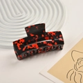 Detail of a rectangular acetate hair claw clip featuring a red and black floral pattern - Black Red Floral Pattern