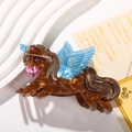 Dettaglio del fermaglio a forma di leone tartarugato con ali azzurre su piatto bianco - Unicorno Marrone