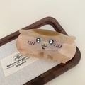 Macro shot of a cartoon cat hair claw clip in amber acetate on a wooden display tray - Shy Cat