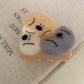 Detail view of acetate claw clip with three cartoon dogs on a book background - Khaki