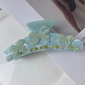 Détail d'une pince à cheveux bleu clair avec des strass en forme de papillons - 11cm / Bleu
