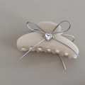Detail of a cream acetate hair claw featuring a silver ribbon bow and a heart zircon - 10cm / White