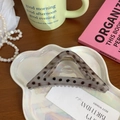 Dettaglio molletta a triangolo grigia trasparente con pois neri su vassoio bianco - Grigio