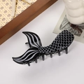 Detail of fishtail hair claw featuring black finish with white fish scale texture - Black