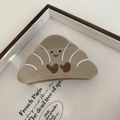 Detail view of croissant shaped brown acetate hair claw clip with cute heart on a tray - Croissant