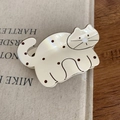 Close-up of cute cream cat hair claw clip with brown dots on a rustic wooden table - White