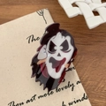 Detail view of Scream-style ghost hair claw clip on canvas background with rustic wood decor - Ghostface