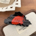 Macro detail of gothic claw clip featuring white spider web patterns and a red heart design - Heart