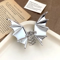 Makro-Detail der silbernen Fledermaus-Haarklammer aus Metall auf Vintage-Buchseiten - 10,1 cm / Silber