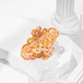 Detail of a marble textured Chinese knot hair claw clip on a white stone pedestal - Orange (QY0082)