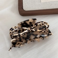 Detailed view of large leopard print acetate hair claw clip on neutral striped fabric - Large Style / Light Tortoise - Bow Claw Clip