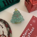 Nahaufnahme einer glitzernden grünen Acryl-Weihnachtsbaum-Haarklammer mit Festtagsdekoration - Weihnachtsbaum