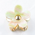 Détail macro d'une pince à cheveux fleur en acétate avec des accents métalliques dorés - vert clair