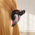 Detalle de una pinza para el cabello de flamenco oscuro en un peinado con cabello rubio - Negro