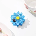 Detail of blue daisy acetate hair claw clip with yellow center and ladybug accent - Medium / Sky Blue
