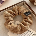 Detailed view of dark camel knit hair scrunchie with 100% polyester label on linen - 10cm / Khaki