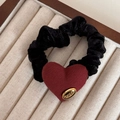 Macro detail of red heart fabric hair tie with engraved gold metal label in display box - Gold Label Red - Heart Hair Rope