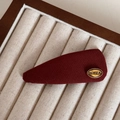 Macro-opname van een rode stoffen haarklem met gouden Korea-embleem op een fluwelen tray - Druppel Gebreide BB Clip