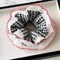 Detailed macro view of black and white checkered hair scrunchie with red wavy lace trim - Black and White Plaid Lace