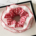 Detalle de coletero de encaje a cuadros rojos y blancos en una caja de regalo - Cuadros Rojo
