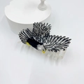 Dettaglio della creativa molletta per capelli ad aquila con piume bianche e nere e becco - Stile Aquila