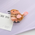 Detailed close-up of a bird-shaped acetate hair claw clip with pink wings on a purple tray - Pinkish Bird