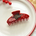 Macro view of red acetate shark hair claw featuring a black snake with gold moon stars - Red