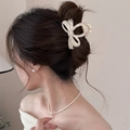 Detail of cream marbled bow hair claw clip styled on woman's updo hairstyle - Beige Bow Claw Clip