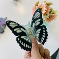 Dettaglio del fermaglio a farfalla con texture floreale e molla in metallo dorato - Farfalla con Motivo Nero Verde