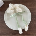 Dettaglio dell'elastico per capelli color crema con fiocco verde su piatto di porcellana - Scrunchie Tulipano Beige