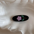 Close-up of black oval hair clip with purple floral patterns and crystal detail - Black