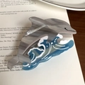 Detailed macro view of a dolphin-shaped acetate hair claw with blue ocean wave patterns - 12cm / Gray