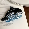 Detail of dolphin hair claw clip made of acetic acid resin on a book background - 12cm / Black