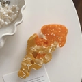 Makro-Detail einer großen Acetat-Haarklammer mit gelbem Marmormuster und Quallen-Design - Orangefarbene Qualle