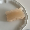 Detail of champagne wavy biscuit hair claw clip with fine glitter in white porcelain dish - Yellow