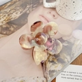Gros plan détaillé d'une pince à cheveux fleur en acétate avec texture marbrée sur un magazine - Violet Raisin