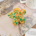 Détail de la pince à cheveux fleur en acétate avec texture marbrée jaune et verte sur magazine - Jaune-Vert Tropical