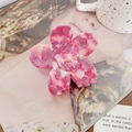 Vue détaillée de la pince à cheveux fleur rose en acétate avec une texture lisse et brillante - Rose Rouge