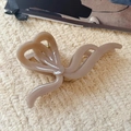 Close-up of a large nude bow-shaped hair claw clip on a textured beige background - Milk Coffee-13cm