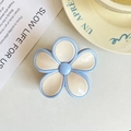Detailed view of the blue and cream frangipani flower hair claw clip on a book - Blue Edge White Flower