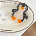 Close-up of a cute penguin-shaped acetate hair claw clip on a white decorative plate - Penguin