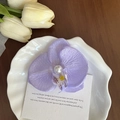 Detailed macro of a purple silk orchid hair clip featuring a large pearl center piece - Purple