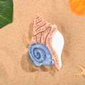 Detailansicht der Meeresmuschel-Haarklammer mit glitzernden Strasssteinen auf Sand - Schnecke Haarklammer