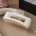 Dettaglio di una grande pinza per capelli color crema su fondo in legno materico - 10.5cm / Bianco